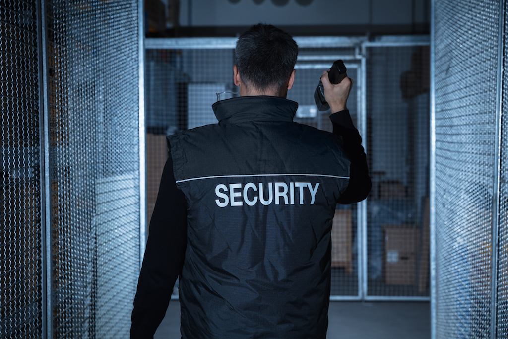 warehouse security 1st Class Protection Security guard checking warehouse at night with torch